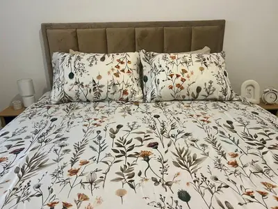 a bed with a floral comforter and two pillows at Lumière Apartment in Banja Luka