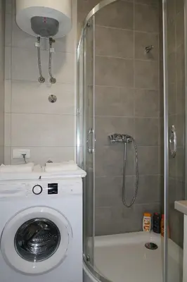 a washing machine in a bathroom with a shower at Lumière Apartment in Banja Luka