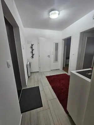 a living room with a red rug and a kitchen at Apartment STELLA in Bihać