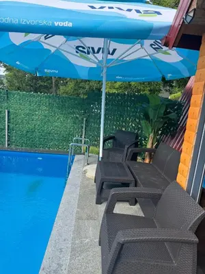 two chairs under an umbrella next to a swimming pool at AM Pyramid resting in Visoko
