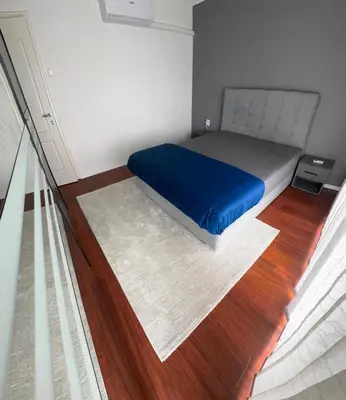 a bedroom with a bed with blue sheets and wood floors at Elmo Oasis in Banovići