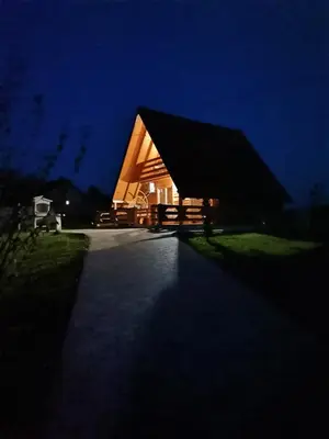 a wooden house with a large roof at night at Brvnara N&N in Laktaši