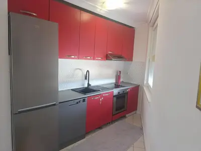 a kitchen with red cabinets and a sink at CityComfort Tuzla in Tuzla