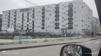 a large white building with cars parked in a parking lot at Comfort pored Klinickog Centra in Banja Luka