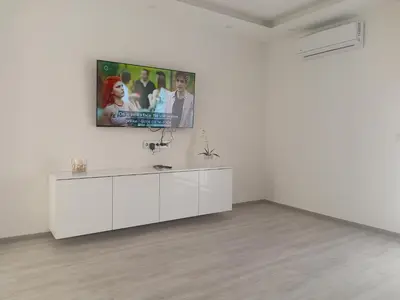 a white living room with a tv on a wall at Apartman Volijak 44 in Jajce