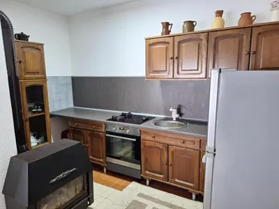 a kitchen with wooden cabinets and a sink and a refrigerator at Relax Rose Apartment in Kulen Vakuf