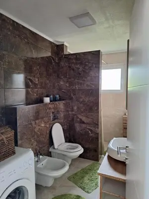 a bathroom with a toilet and a sink and a washing machine at Relax Rose Apartment in Kulen Vakuf