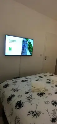 a flat screen tv hanging on a wall above a bed at Apartman Bonaca in Kiseljak