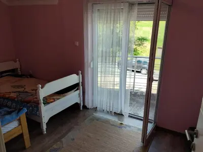 a bedroom with a bed and a sliding glass door at Lillis Apartment in Ivišovo Greblje
