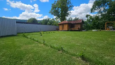 a yard with a wooden cabin in the background at Smjestaj na selu KLARA in Staro Selo