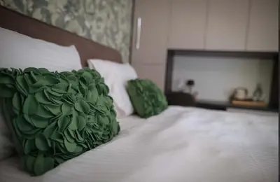 a bed with a green pillow on top of it at Una Meryland in Kulen Vakuf