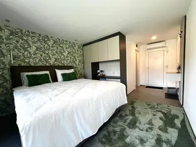 a bedroom with a large white bed and a green rug at Una Meryland in Kulen Vakuf