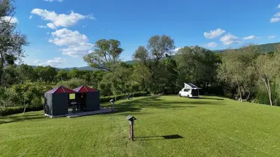 a large grassy field with two tents and a van at Una Meryland in Kulen Vakuf