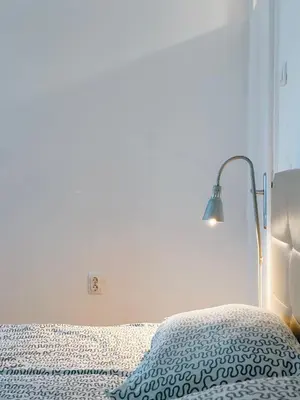 a white bedroom with a bed with a lamp at Apartman Lorka in Banja Luka