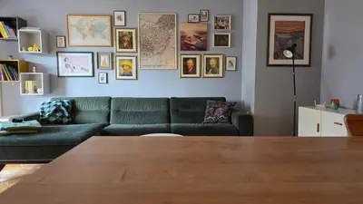 a living room with a green couch and pictures on the wall at Apartman Lorka in Banja Luka