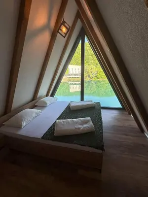 a bed in a room with a large window at Vikendica Hamza in Bihać