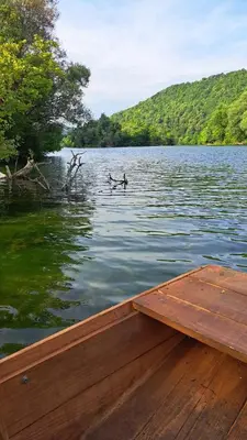 a wooden boat on a lake with a bird in the water at Vikendica Hamza in Bihać