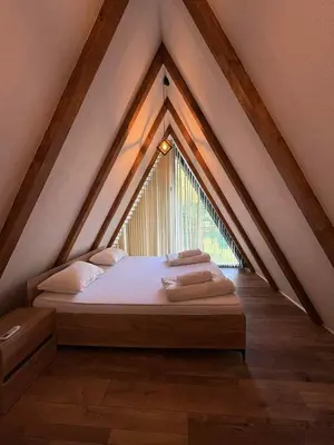 a bed in a attic with a large window at Vikendica Hamza in Bihać