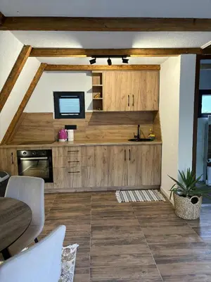 a large kitchen with wooden cabinets and a television at Vikendica Hamza in Bihać