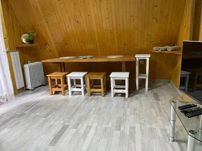 a room with a wooden table and four stools at Planinska kuća Divna in Šišava