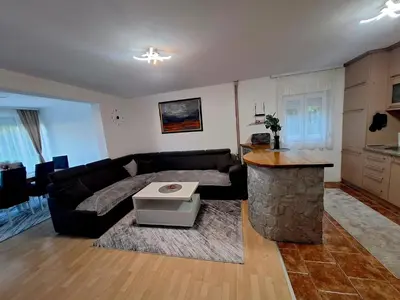 a living room with a black couch and a kitchen at Villa Forest in Bosanska Gradiška