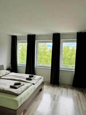 a bedroom with a bed and two windows at Sobe PALMA in Sanski most