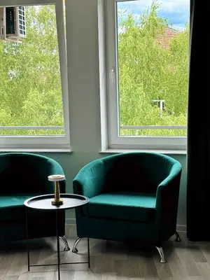 two green chairs and a table in front of a window at Sobe PALMA in Sanski most