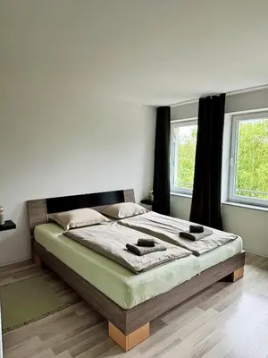 a bedroom with a large bed in front of two windows at Sobe PALMA in Sanski most