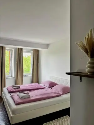 a bedroom with a large bed with purple sheets and pillows at Sobe PALMA in Sanski most