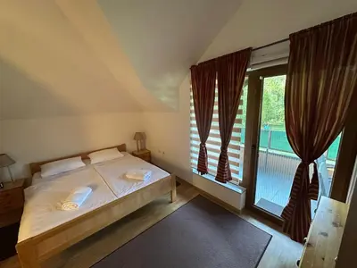 a bedroom with a bed and a large window at Cottage on Una in Bihać