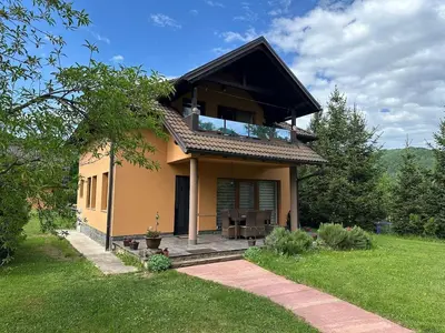 a small yellow house with a porch in a yard at Cottage on Una in Bihać