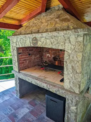 an outdoor stone fireplace with a brick wall at Vikendica Stella in Bihać