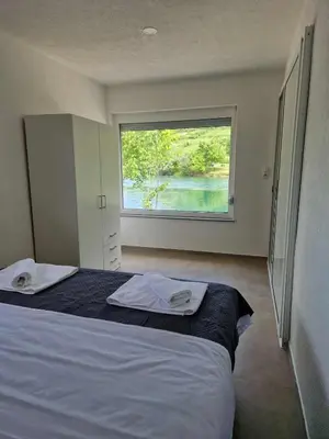a bedroom with a bed with a large window at Apartman A&A in Ivišovo Greblje