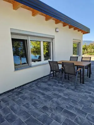 a patio with a wooden table and chairs and windows at Apartman A&A in Ivišovo Greblje