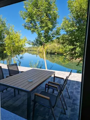 a wooden table and chairs with a view of a lake at Apartman A&A in Ivišovo Greblje