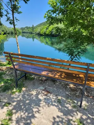 a wooden bench sitting next to a river at Apartman A&A in Ivišovo Greblje