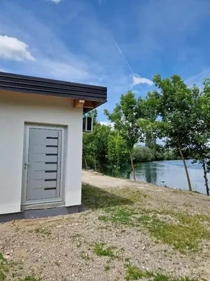 a building with a garage next to a river at Apartman A&A in Ivišovo Greblje