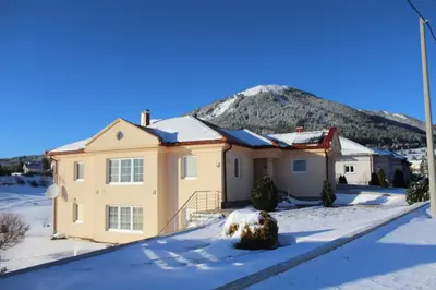 a house in the snow with a mountain in the background at Kuća za odmor KUNA in Kupres