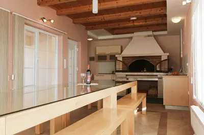 a kitchen with a dining table and a fireplace at Kuća za odmor KUNA in Kupres