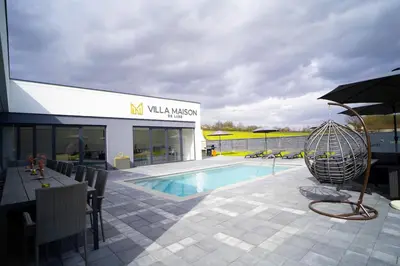 a swimming pool with an umbrella next to a building at Villa Maison de luxe in Laktaši