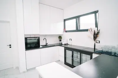 a kitchen with white cabinets and a black counter top at Villa Maison de luxe in Laktaši