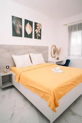 a white bedroom with a large bed with an orange blanket at Villa Maison de luxe in Laktaši