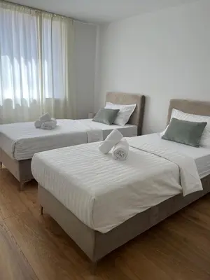two twin beds in a room with white walls at Apartmani Pervan 2 in Livno