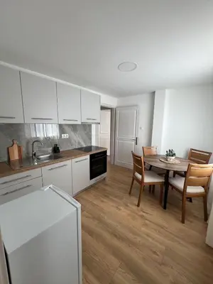 a kitchen with white cabinets and a table and chairs at Apartmani Pervan 2 in Livno