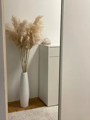 a white vase with feathers in it in a mirror at Apartman I&T in Banja Luka