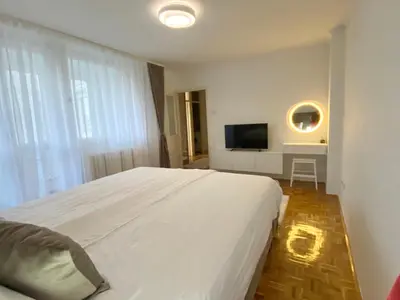 a bedroom with a large white bed and a television at Apartman I&T in Banja Luka