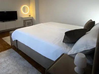 a large white bed in a room with a tv at Apartman I&T in Banja Luka