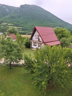 a house with a red roof in a field with trees at Vikendica 