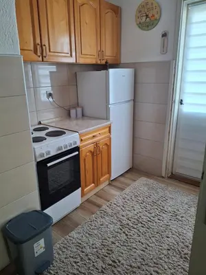 a kitchen with wooden cabinets and a stove and refrigerator at Vikendica 
