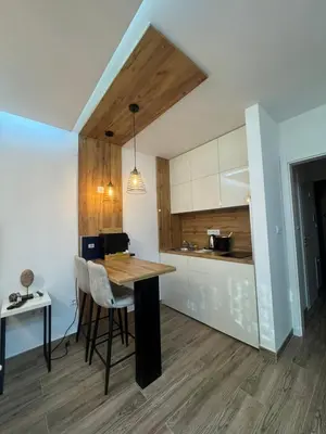 a kitchen with a wooden table and a dining room at Belvedere Apartment in Doboj